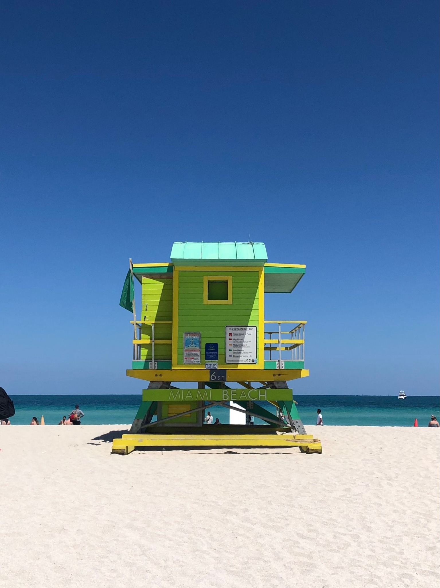 Green and yellow Miami Beach lifeguard tower under a deep blue sky